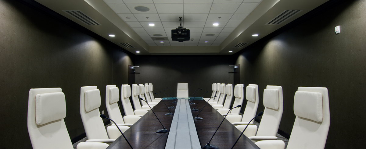 A large conference room with white chairs and a long table.