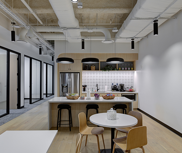 A modern office kitchen with updated appliance and wood features on the cabinets and floors.