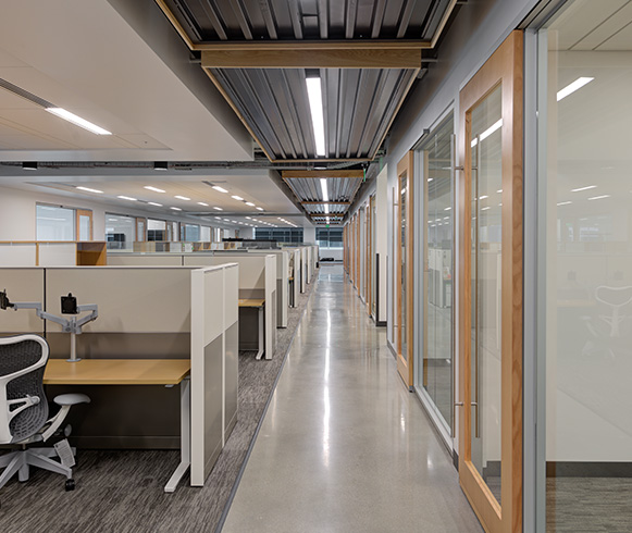 A hallway with conference rooms on the right and cubicles on the left.