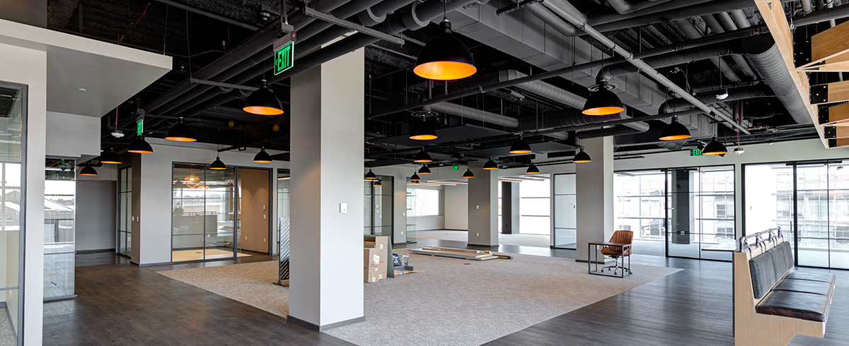 An open floor plan office space with a lot of windows bringing in natural light.