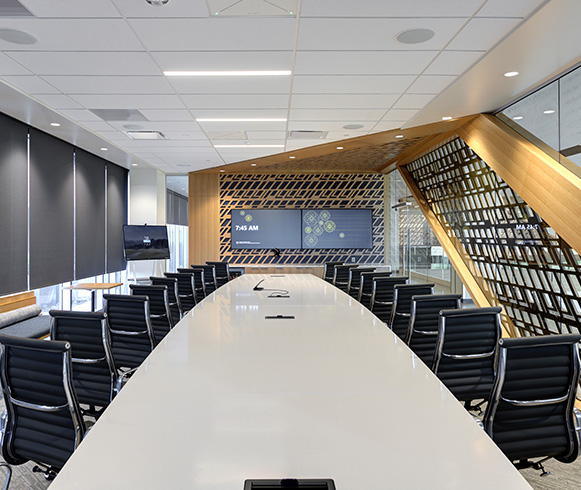 A large conference room with a long white table and black chairs.