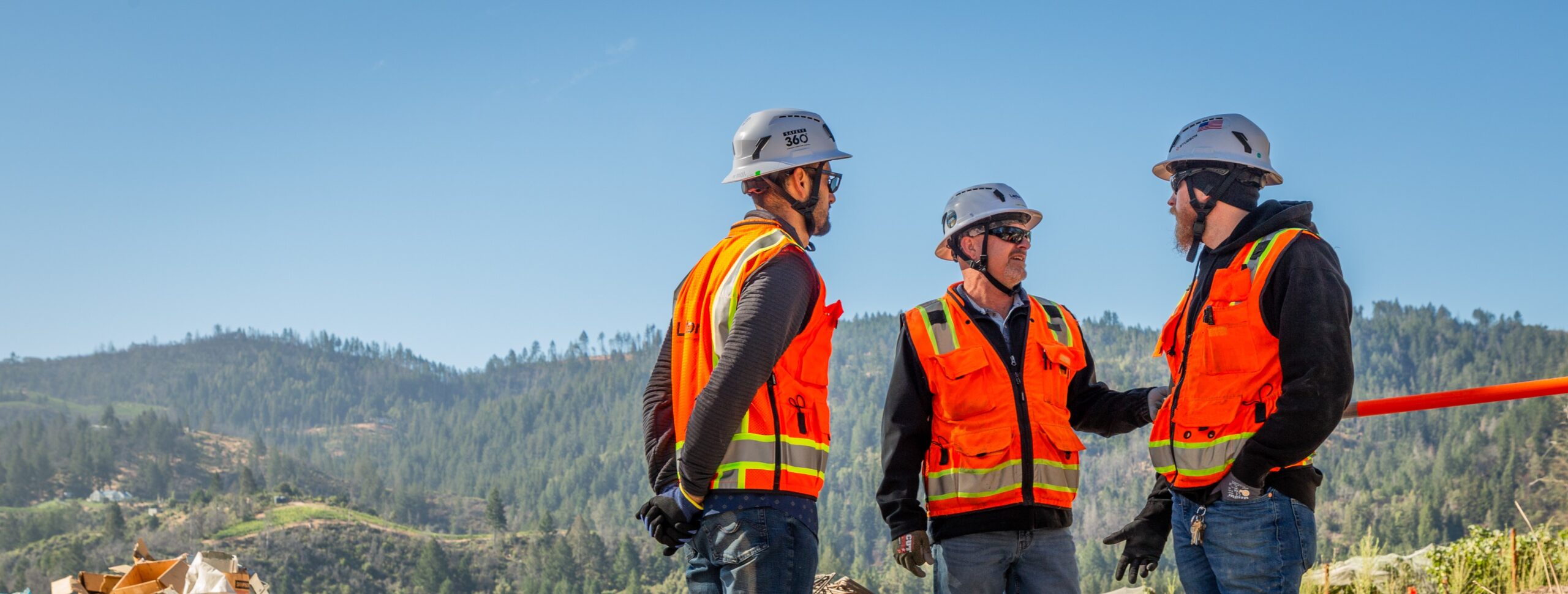 Three employees on a mountainous Northern California jobsite wearing PPE.