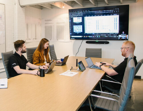 Project team in a trailer with production tracking software on a TV screen