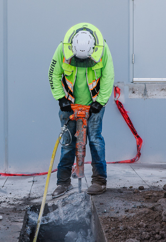 A Trade Partner with a Jack Hammer in a Trench