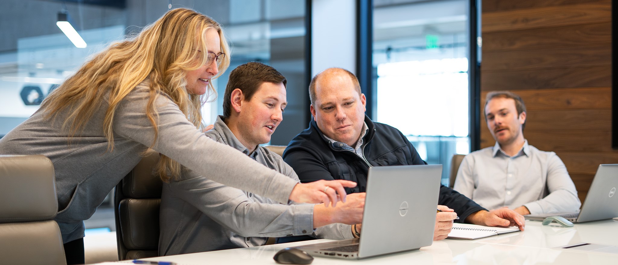 A team of estimators gathered around a computer in a conference room